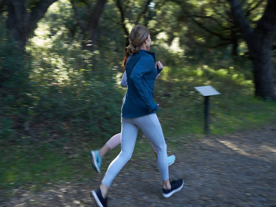 Two women jogging in a park, heading home for a relaxing hot tub soak.