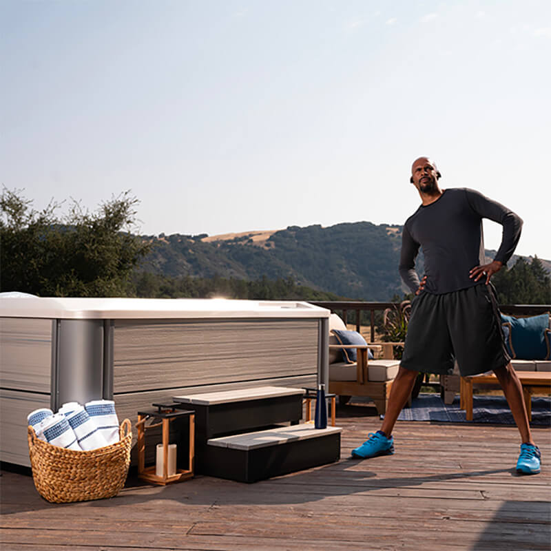 Man stretches after a workout next to a Hot Spring Spas hot tub, primed to experience the increased mobility benefits of hydrotherapy.
