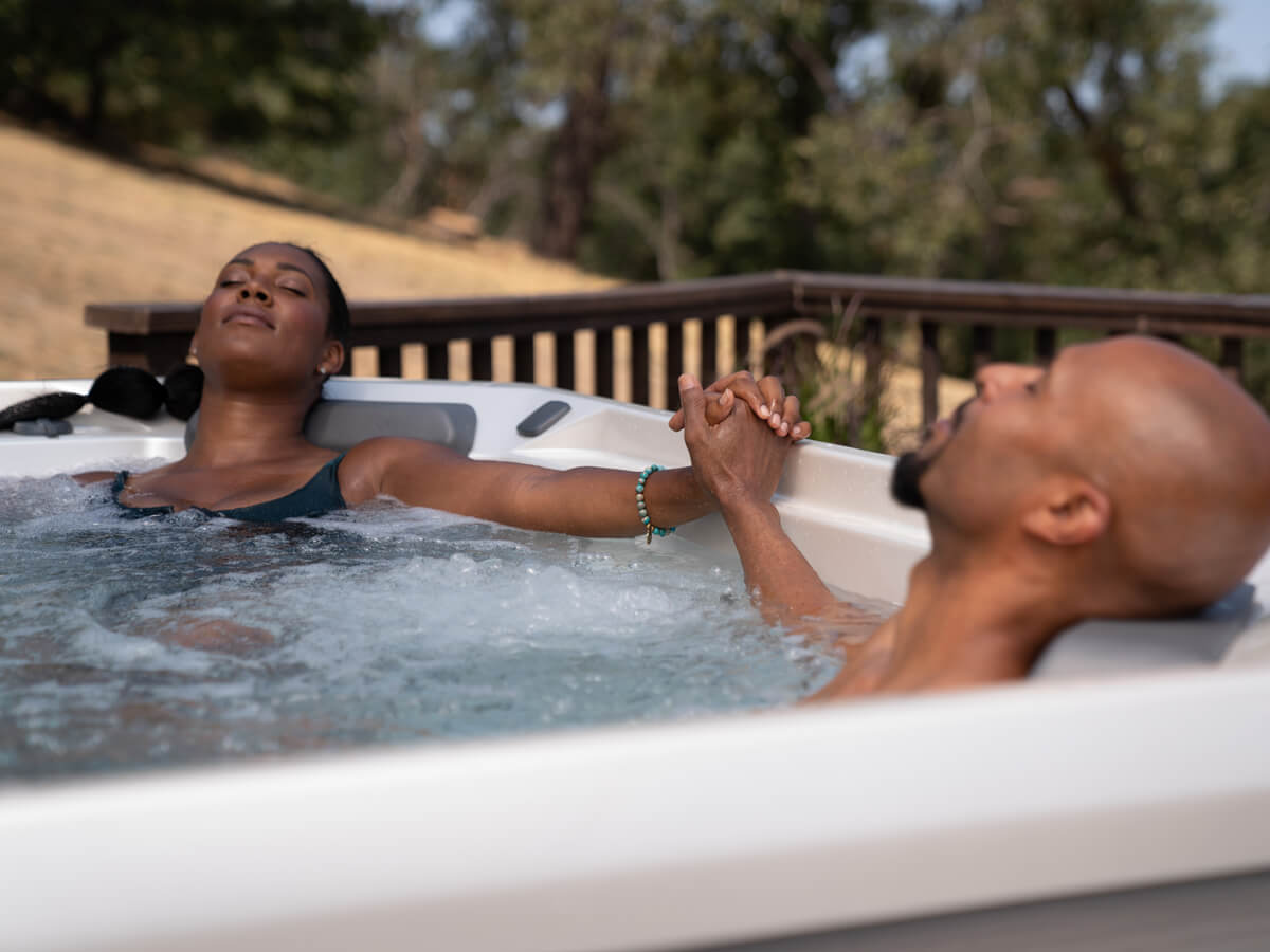 Couple relaxing in Hot Spring Spas hot tub, enjoying the hydrotherapy benefits of muscle relief and stress reduction.