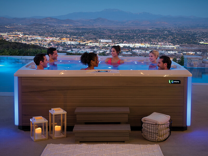 Friends relaxing in a Hot Spring Spa hot tub surrounded with mood lighting, creating a home spa atmosphere.