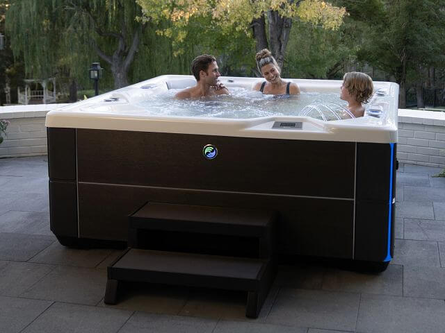 A family enjoys a relaxing soak in their Highlife Vanguard hot tub in their backyard.