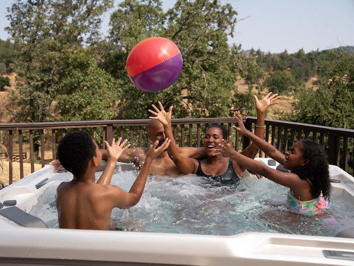 A family of four splashing around and laughing together in a chlorine hot tub.