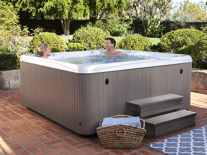 couple relax in their hot tub in the back yard