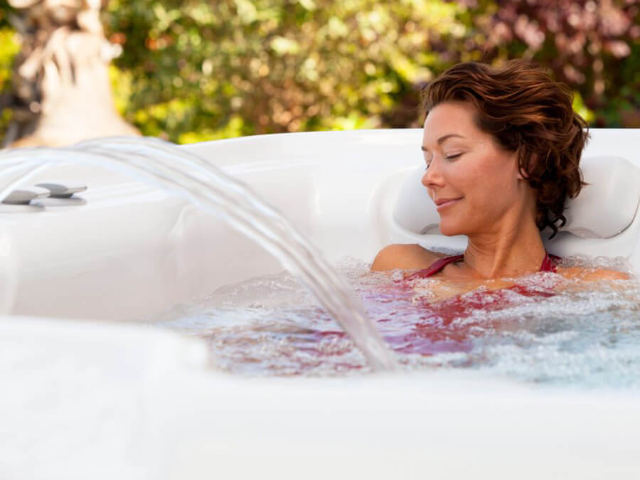 Woman enjoying the soothing water cascade in her Sovereign hot tub from Hot Spring Spas, experiencing ultimate relaxation.